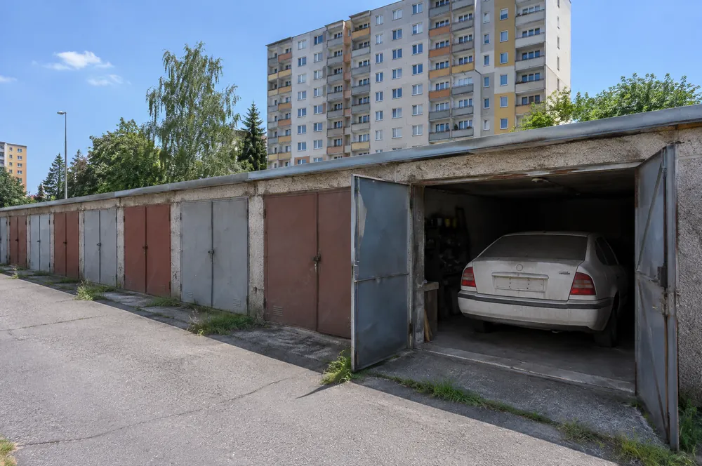 Řada řadových garáží na okraji sídliště, v otevřené garáži stará Škoda Octavia